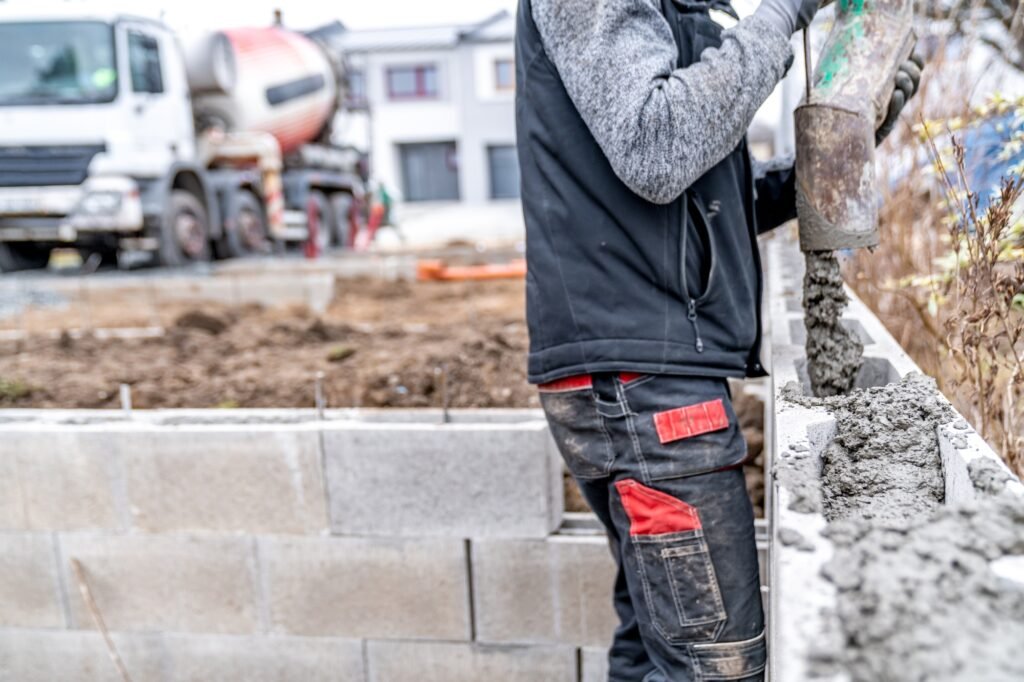 pouring concrete from a mixer truck with a hose into the foundation of the house