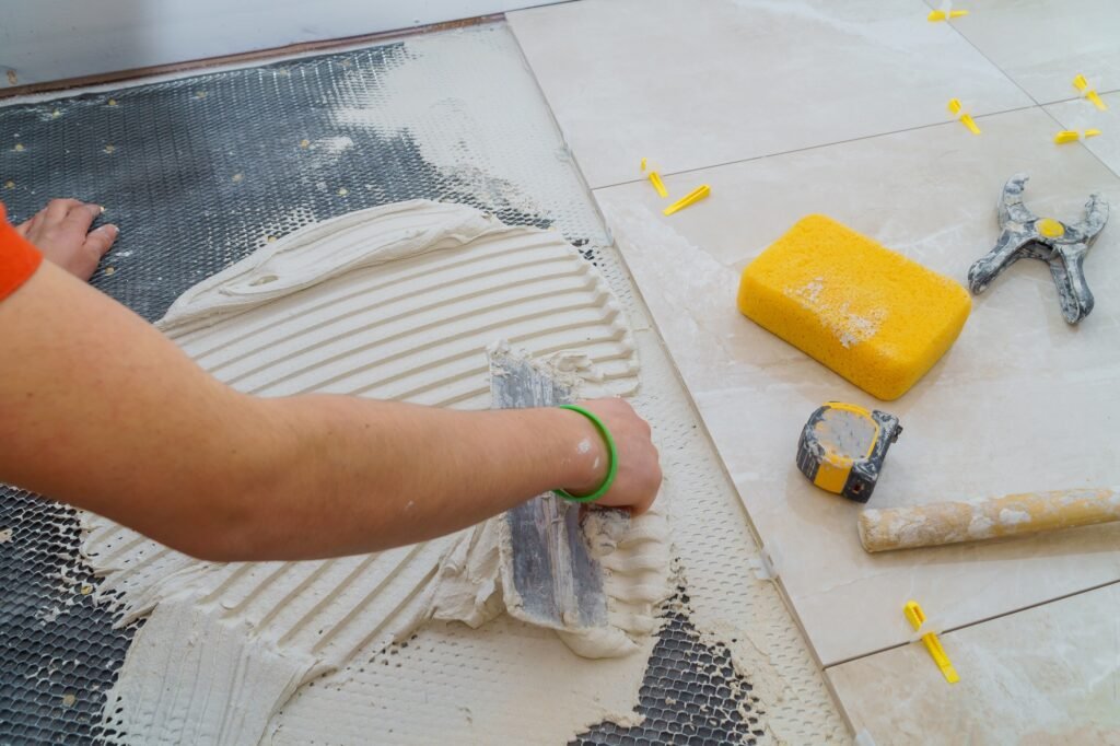 Troweling mortar onto a concrete floor in preparation for laying floor tile.