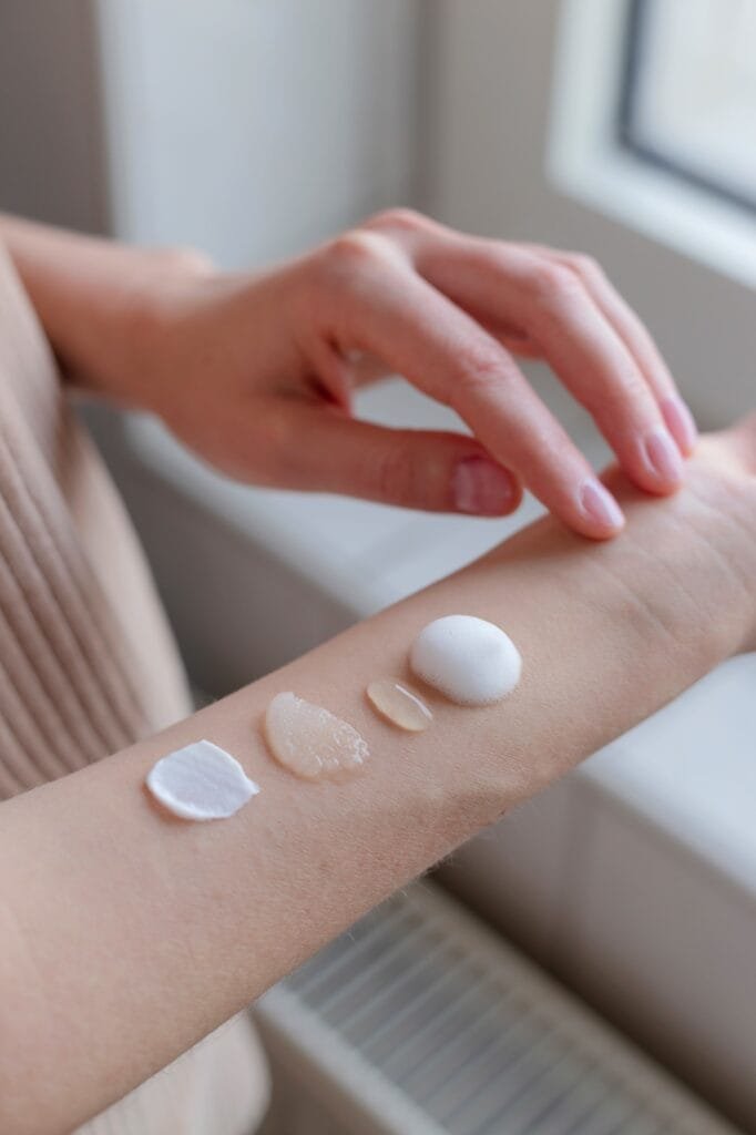 Olika texturerade hudvårdsprodukter på kvinnans hand.