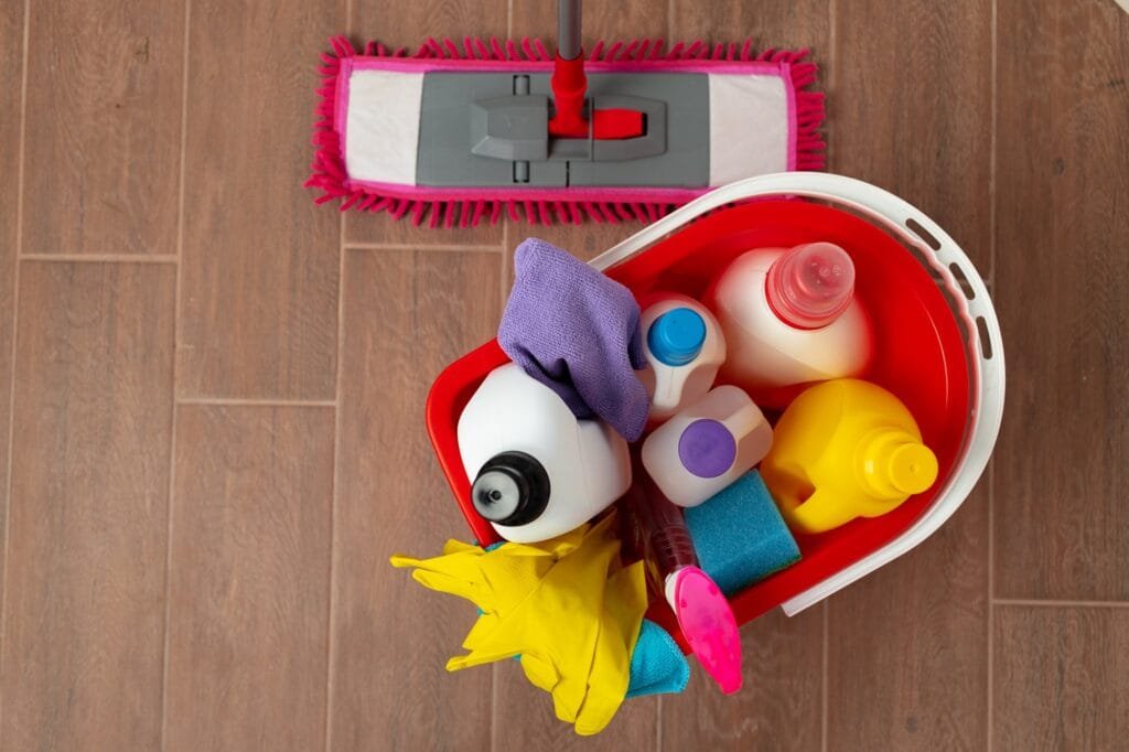 Różne domowe detergenty i butelki w plastikowym wiadrze na podłodze