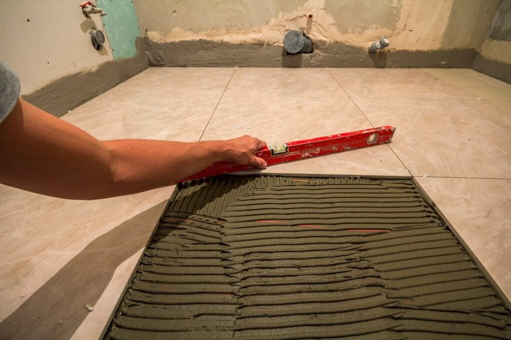 Carreaux de céramique et outils de carreleur. Ouvrier posant à la main des carreaux de sol.