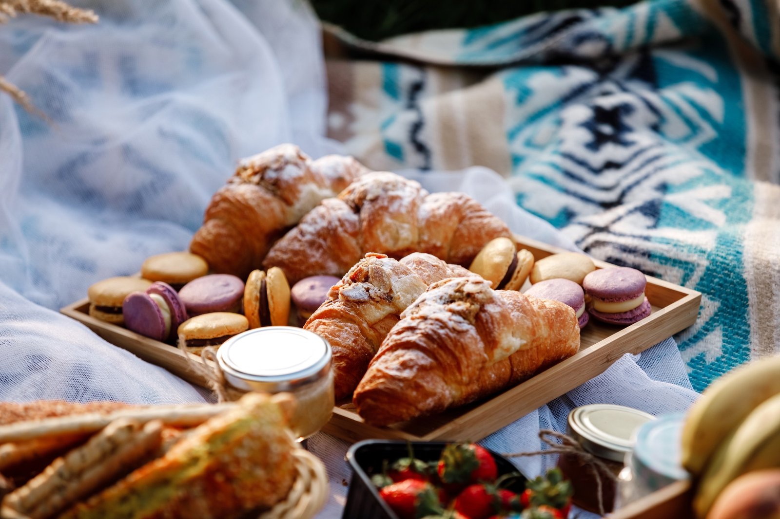 Piknik w parku. Świeże jagody, chleb, dżem, zimne napoje gazowane, kolorowe macarons i c