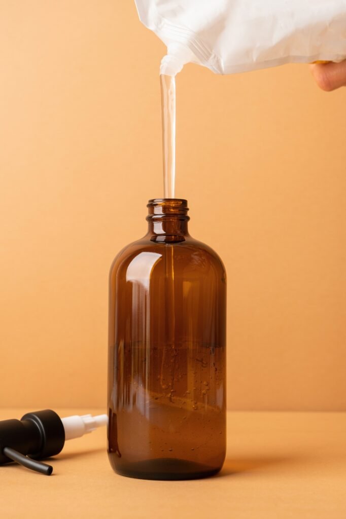 Femme versant du savon liquide d'un emballage en plastique dans une bouteille.